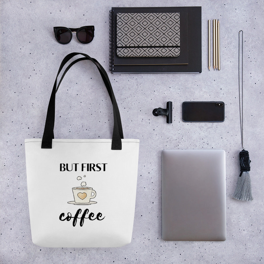 Flat lay of a But First Coffee tote bag beside various daily use items