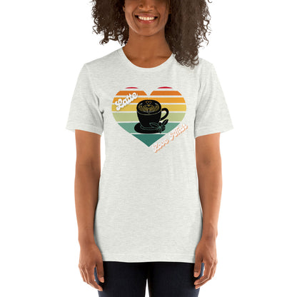 Smiling woman wearing an ash colored coffee t-shirt that has a retro heart sunset and the words Latte Love Affair 