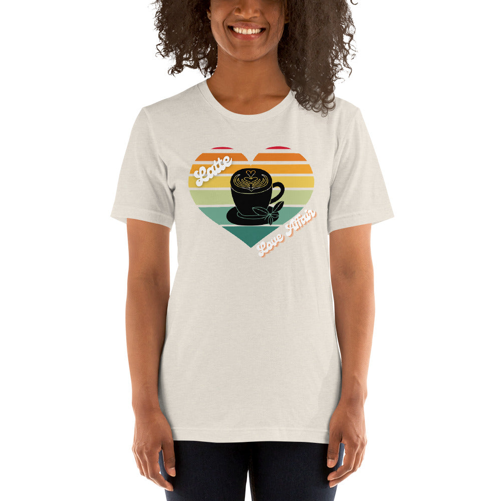 Smiling woman wearing a heather dust coffee t-shirt that has a retro heart sunset and the words Latte Love Affair 