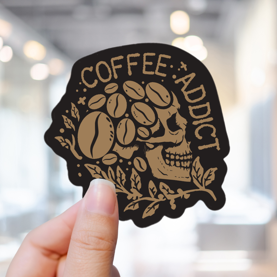 hand holding a sticker of a skull made of coffee beans with the words Coffee Addict