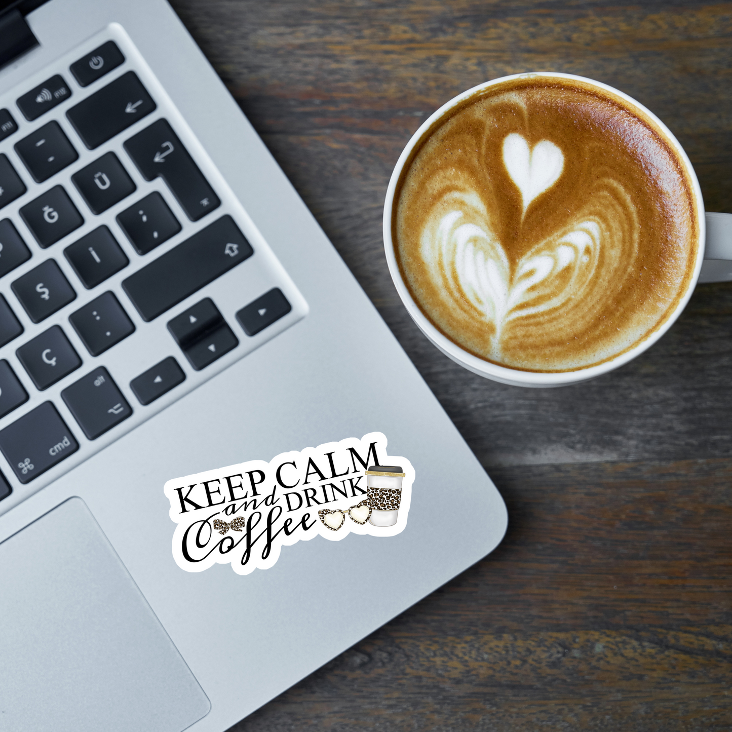 Keep Calm and Drink Coffee sticker on a laptop sitting beside a latte with a steamed milk heart design